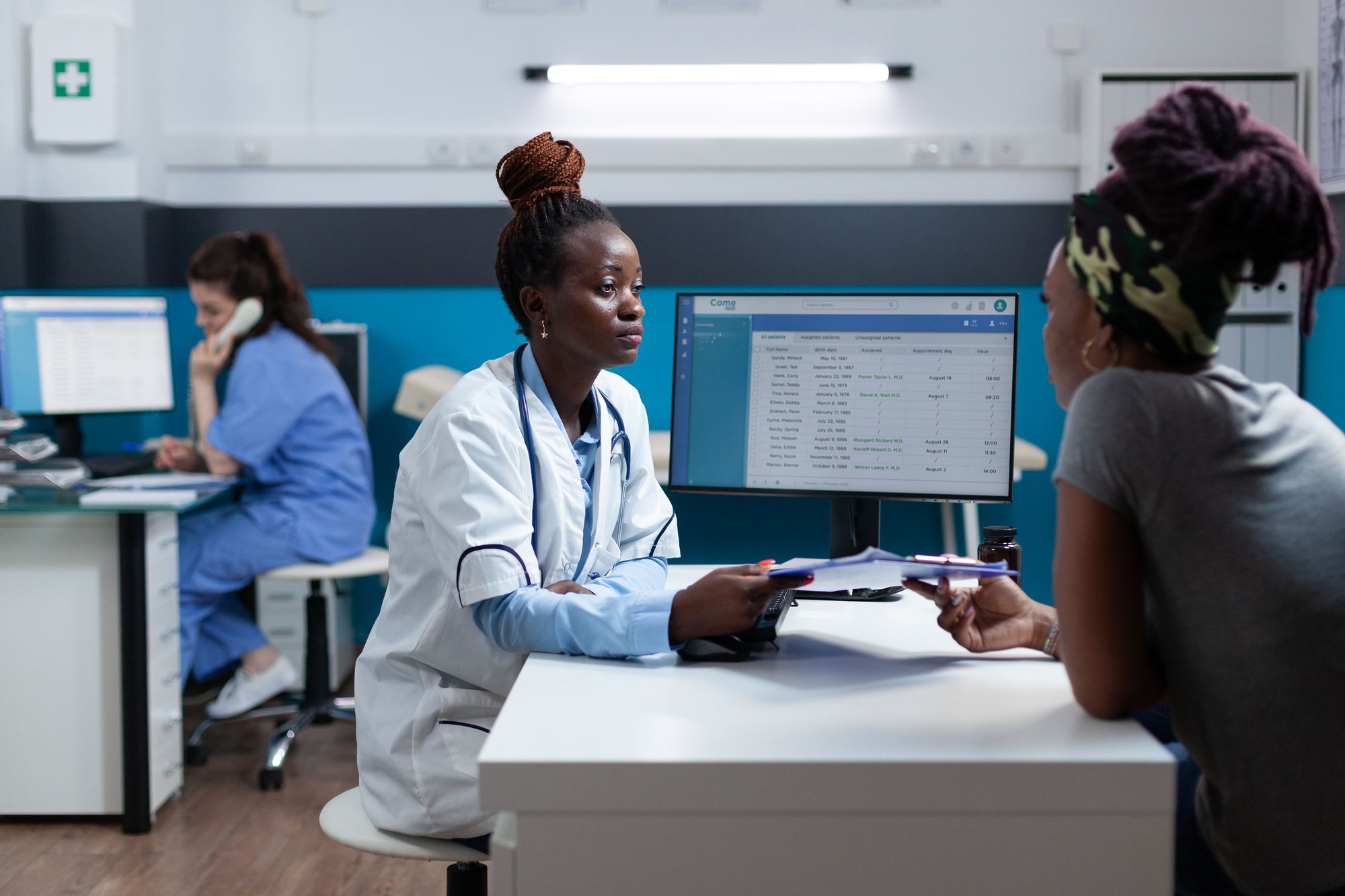 A doctor handing a form to a patient across her desk