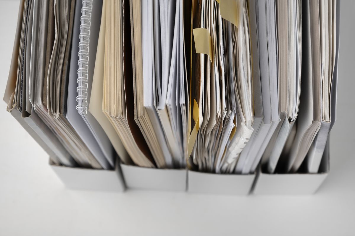 Stacks of paper patient files in box folders